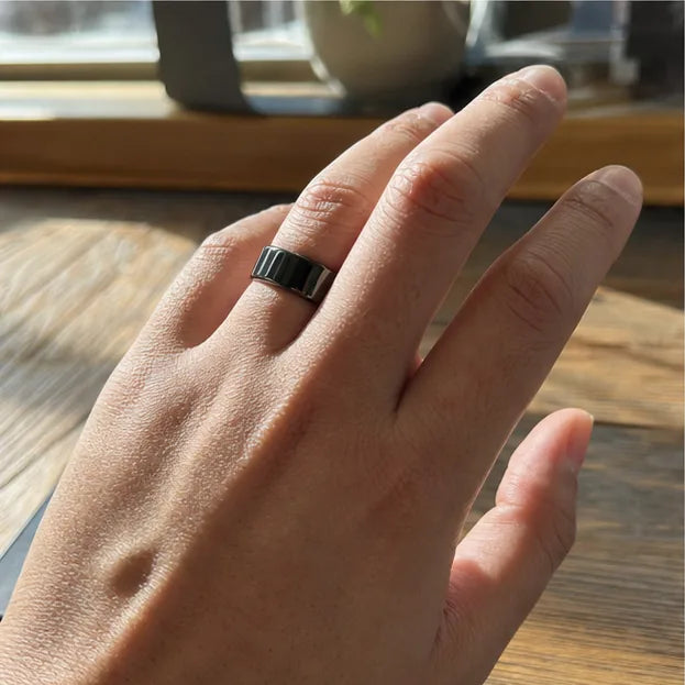A hand wearing the black Quriov Smart Ring while working at a desk.